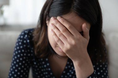 Depresyonda olan Asyalı kadının yüzünü elle kapatması.