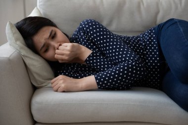 Üzgün, Asyalı genç bir kadın. Kanepede tek başına uzanıp ağlıyor.