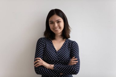 Kollarını kavuşturmuş gülümseyen Asyalı kadın portresi.