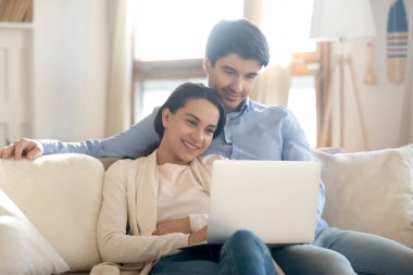 Sevgi dolu genç bir çift kanepede sarılıp dizüstü bilgisayarda film izliyor.