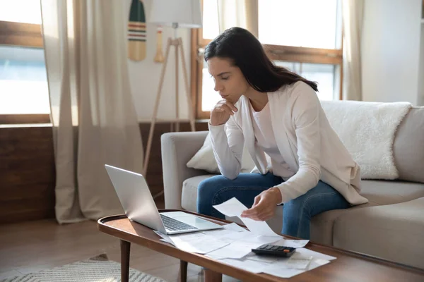 Besorgte junge Frau vergleicht Informationen über Papier und Online-Dokumente — Stockfoto