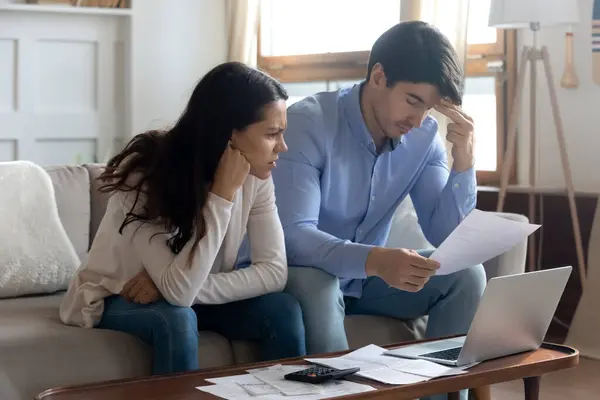 Bezorgd jong getrouwd stel dat bankbrieven bestudeert die informatie geven over schulden — Stockfoto