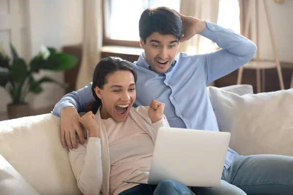Ενθουσιασμένοι οπαδοί ποδοσφαίρου νεαρών συζύγων που παρακολουθούν ποδοσφαιρικό αγώνα χρησιμοποιώντας φορητό υπολογιστή — Φωτογραφία Αρχείου