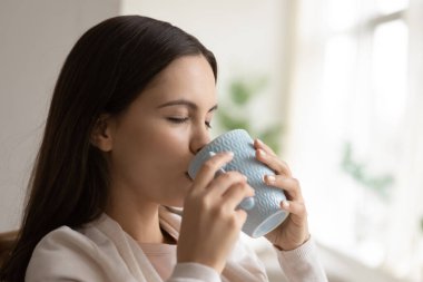 Mutlu genç kadın aromatik kahve çayı içmekten büyük zevk alıyor.