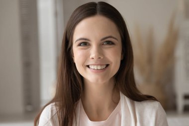 İçerde poz veren güzel, gülümseyen genç bir kadının profil fotoğrafı.