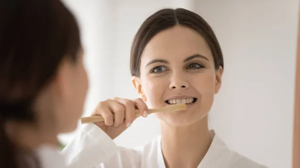 Gelukkig vrouwelijk reinigen tanden in de badkamer met behulp van bamboe eco tandenborstel — Stockfoto