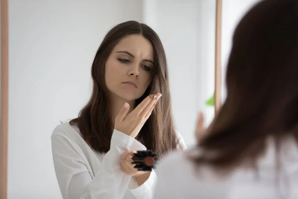 Verstoorde vrouw staat in de badkamer te kijken naar haar zwakke haar — Stockfoto