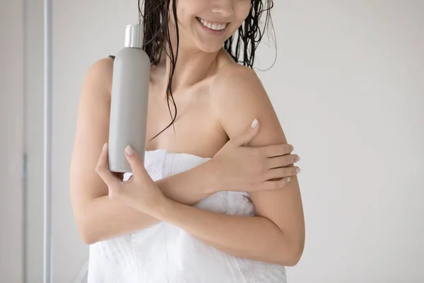 Красивая молодая женщина, завернутая в полотенце с лосьоном на коже — стоковое фото