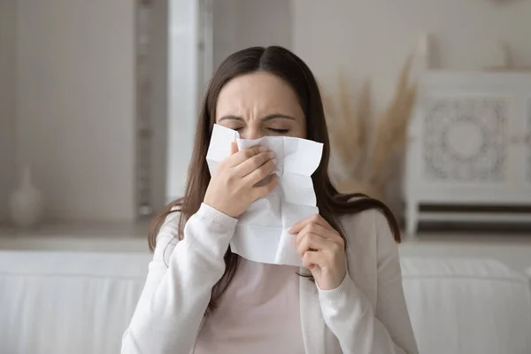 Sick millennial woman having cold blowing nose in paper tissue — Stock Photo, Image