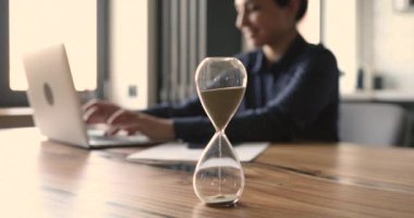 Arka planda çalışan bir kadın olan kum saatine odaklan..