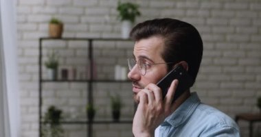 Gözlüklü mutlu genç adam cep telefonuyla arıyor..