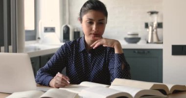 Odaklanmış akıllı melez Hintli kız öğrenci evde çalışıyor..