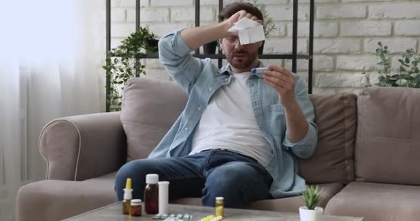 Junger Mann mit Brille hat erste Grippesymptome zu Hause. — Stockvideo