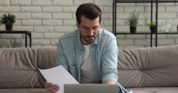 Skoncentrowany młody 30-latek w okularach odwala papierkową robotę finansową.. — Wideo stockowe
