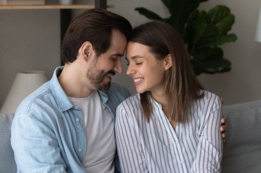 Mutlu çift evde kanepede kucaklaşır.