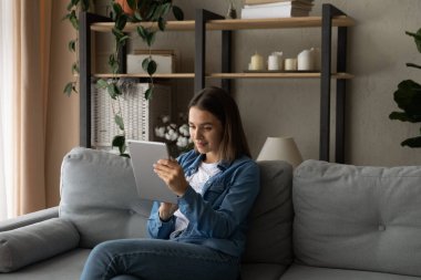 Genç bayan kanepede tablet kullanarak rahatla.