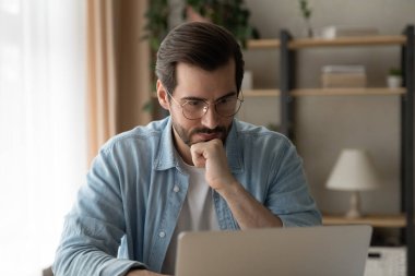 Düşünceli beyaz adam laptop ekranına bak ve düşün.