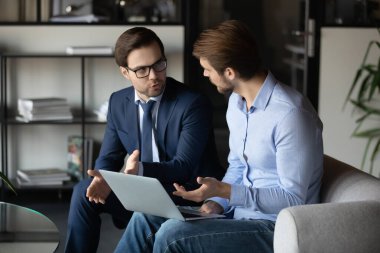 Genç erkek yönetici dizüstü bilgisayar ekranında müşteri sözleşmesi detaylarını açıklıyor