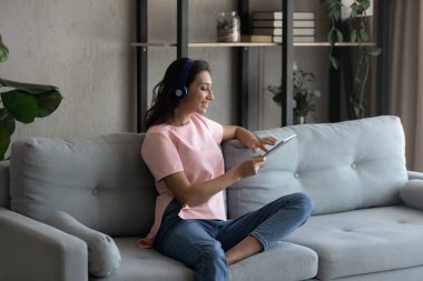 Bilgisayar tableti kullanan, kulaklıklı, rahat, Arap genç bir kadın..