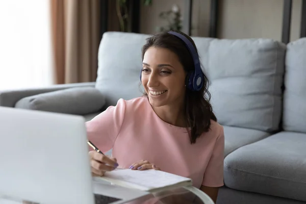 Happy young mixed race woman in headphones enjoying online education.