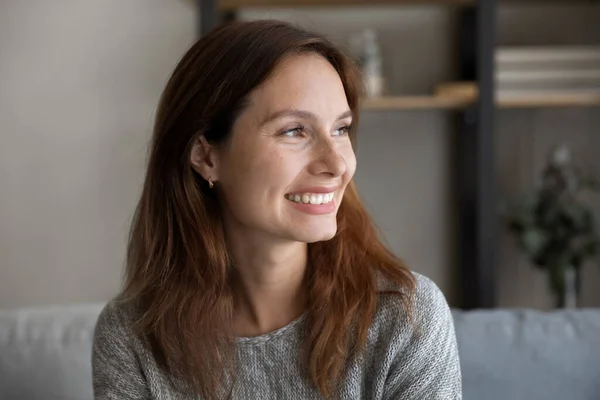 Dreamy happy millennial caucasian woman looking at distance.