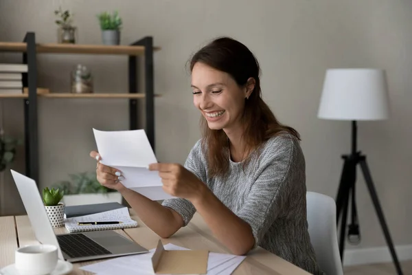 Mujer milenaria sonriente leyendo carta con buenas noticias. — Foto de Stock