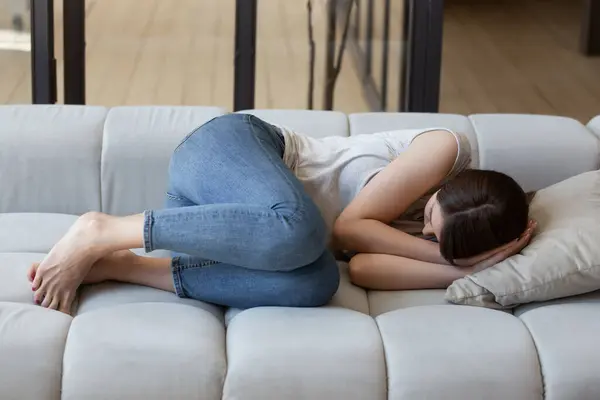 Нещаслива пригнічена молода жінка спить на дивані вдома — стокове фото