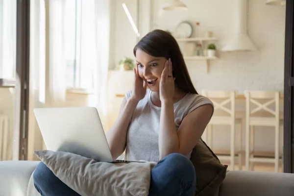 Mujer joven llena de alegría mirando la pantalla del ordenador portátil, leyendo buenas noticias —  Fotos de Stock