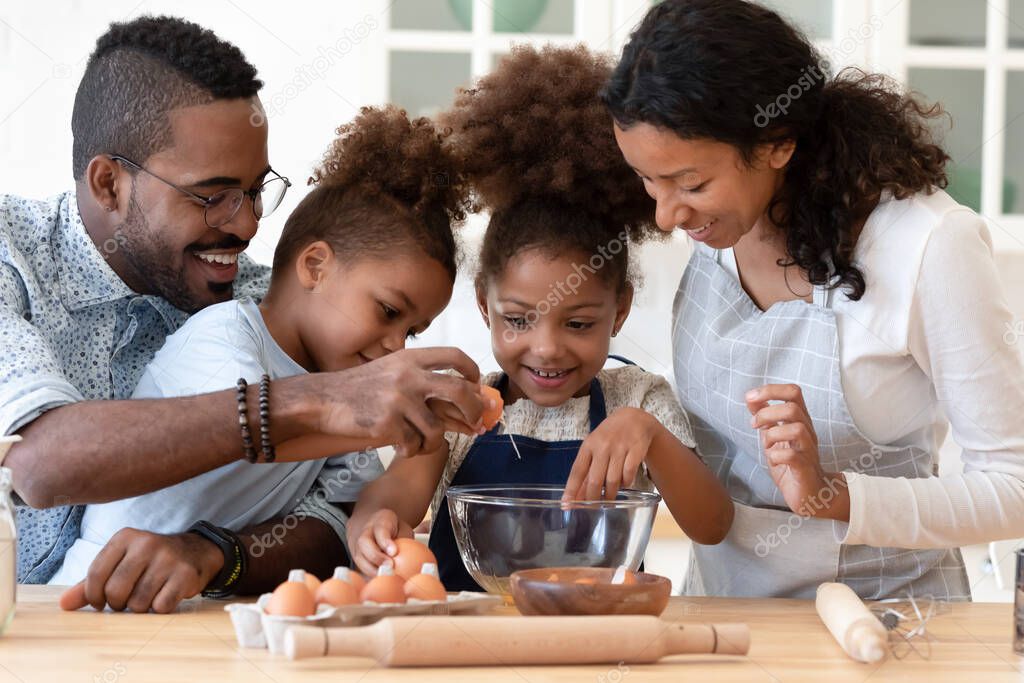 Loving friendly afro american family mixing dough for homemade pastries