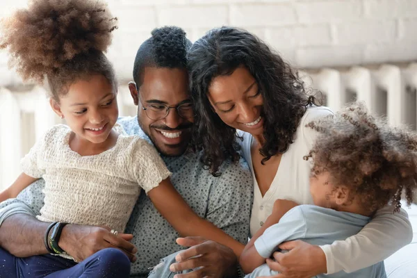 Fröhliche afrikanisch-amerikanische Eltern entspannen sich auf Couch und kitzeln ihre Kinder — Stockfoto