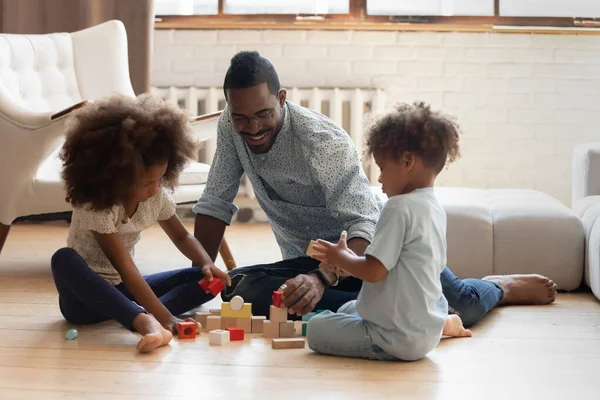 Interessierter schwarzer Vater baut mit Kindern Ziegeltürme — Stockfoto