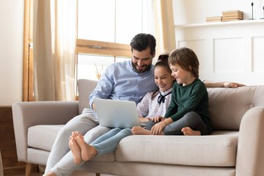 İki çocuklu sevecen baba dizüstü bilgisayarda video izliyor.