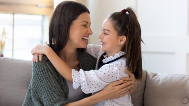 Gülümseyen genç anne ve küçük kız sarılıyor.