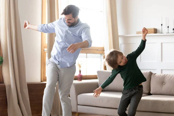 Aufgeregter junger Vater mit kleinem Sohn tanzt zu Hause — Stockfoto