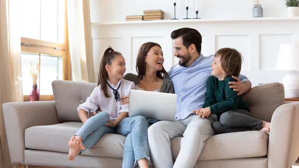 子供のいる幸せな両親はコンピュータを使って家にいます — ストック写真