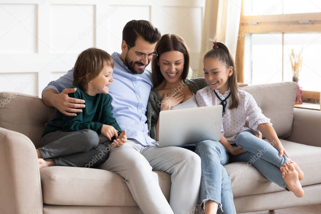 Overjoyed family with children relax at home with laptop
