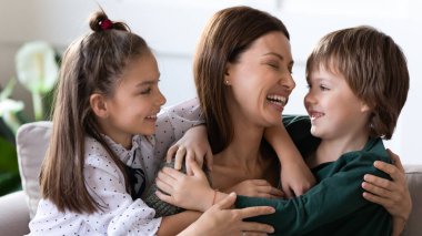 İki çocuk kucaklaşır. Mutlu anne sevgi gösterir.
