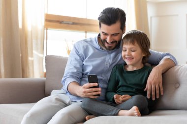 Mutlu baba ve küçük oğlu evde cep telefonuyla rahatlıyor.