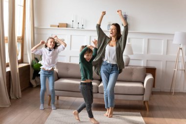 İki çocuklu mutlu anne oturma odasında dans ediyor.