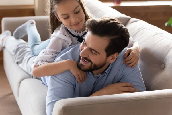 Счастливый молодой папа и маленькая дочь отдыхают на диване — стоковое фото