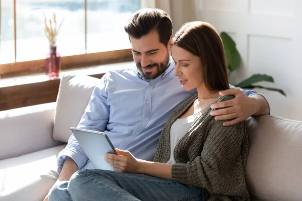 Glückliches Paar entspannt auf Sofa mit Tablet-Gadget — Stockfoto