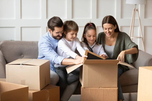 Famiglia eccitata con i bambini disfare le valigie in una nuova casa — Foto Stock