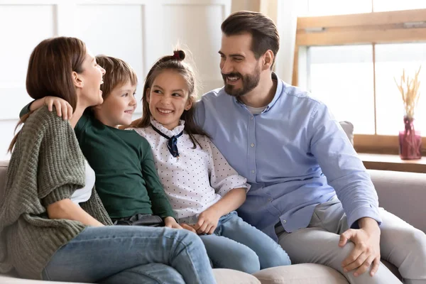 Uśmiechnięta rodzina z dwójką dzieci relaksuje się w domu — Zdjęcie stockowe