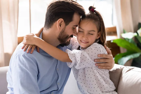 Молодий тато і маленька дочка обіймаються насолоджуючись ніжною миттю — стокове фото