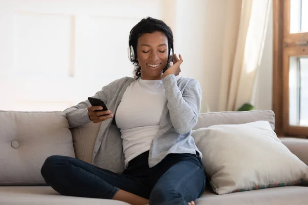 Mujer Biracial en los auriculares utilizan teléfono inteligente moderno — Foto de Stock