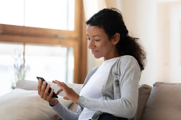 Mujer afroamericana usa gadget de teléfono inteligente en casa — Foto de Stock