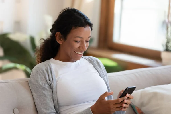 Sonriente mujer biracial mirar mensajes de texto de pantalla de teléfono celular — Foto de Stock