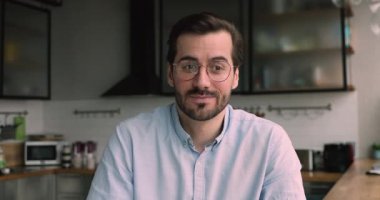 İş adamı mutfakta oturup müşteriyle uzaktan video görüşmesi yapar.