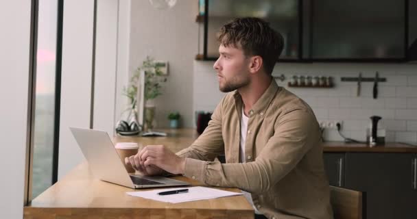 Homme sérieux réfléchi travaillant à distance de la maison à l'aide d'un netbook portable — Video