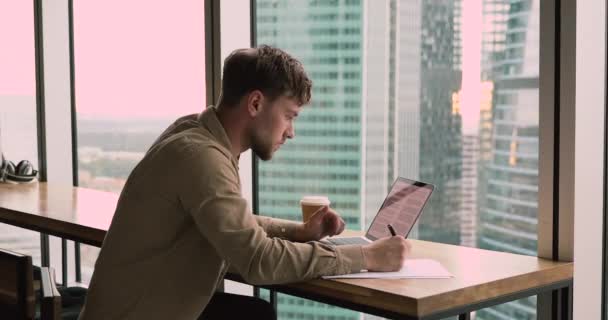 Millennial fyr sitter på moderne arbeidsplass og jobber med laptop – stockvideo